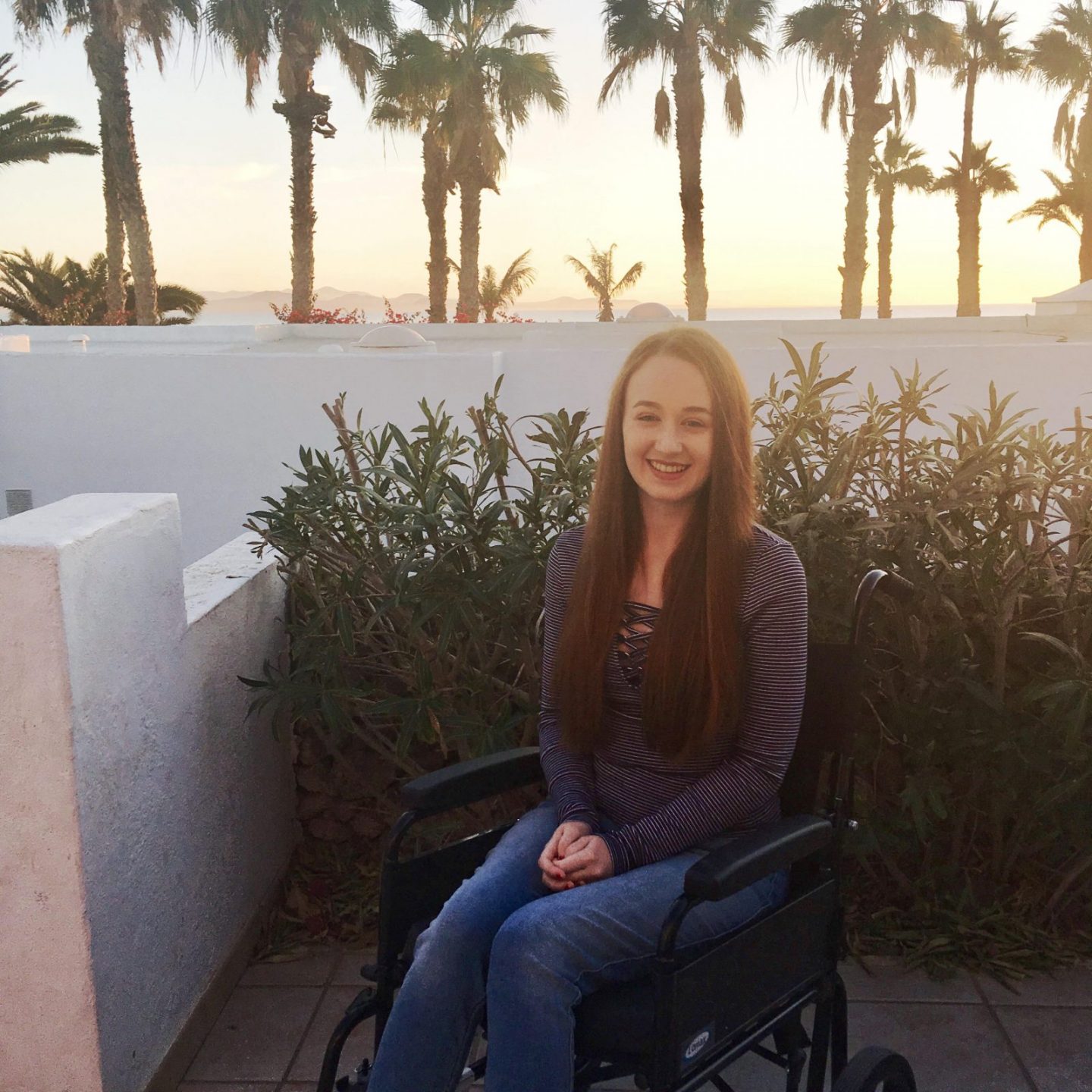 girl in jeans and t-shirt in wheelchair on an outdoor balcony