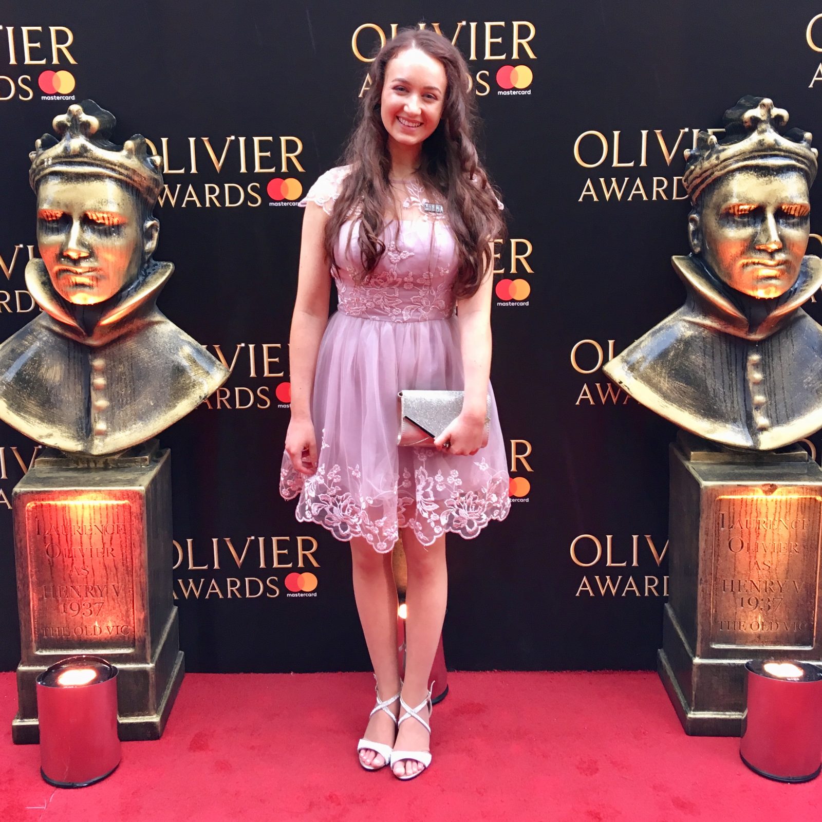 full length image of pippa in pink formal dress stood on red carpet in front of olivier awards photo board