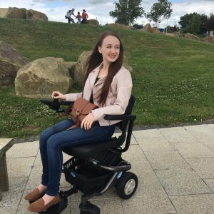 pippa in powerchair looking to right and laughing