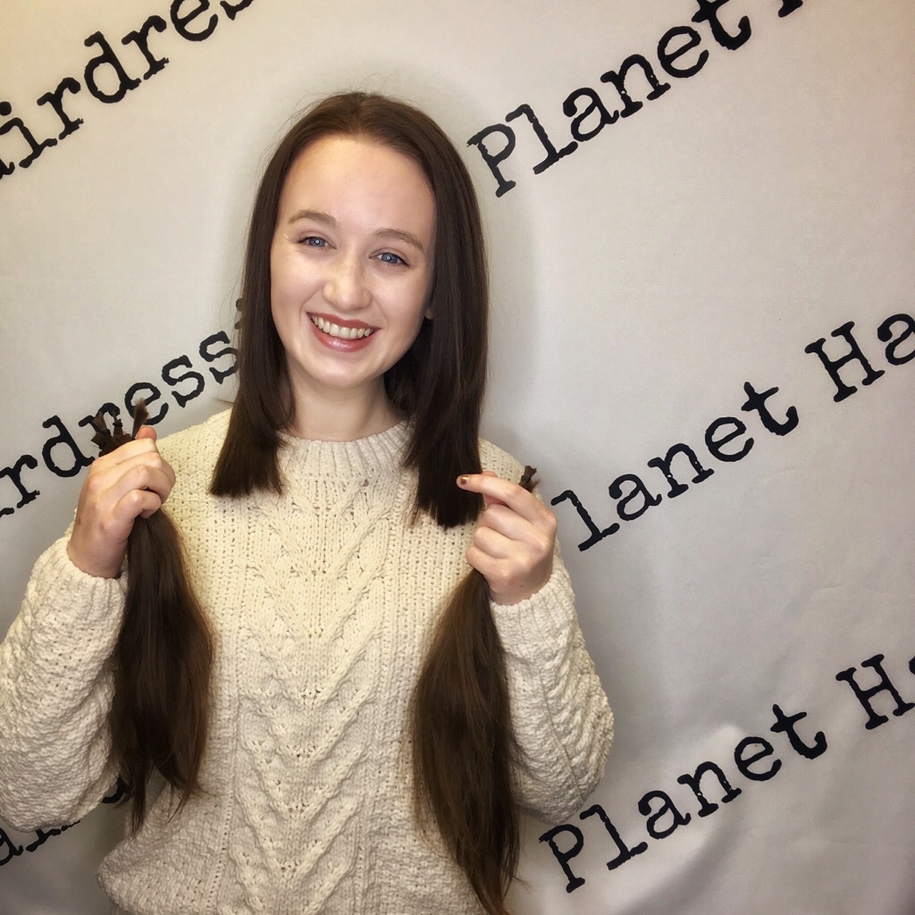 pippa with cropped hair holding locks of cut hair in hands and smiling