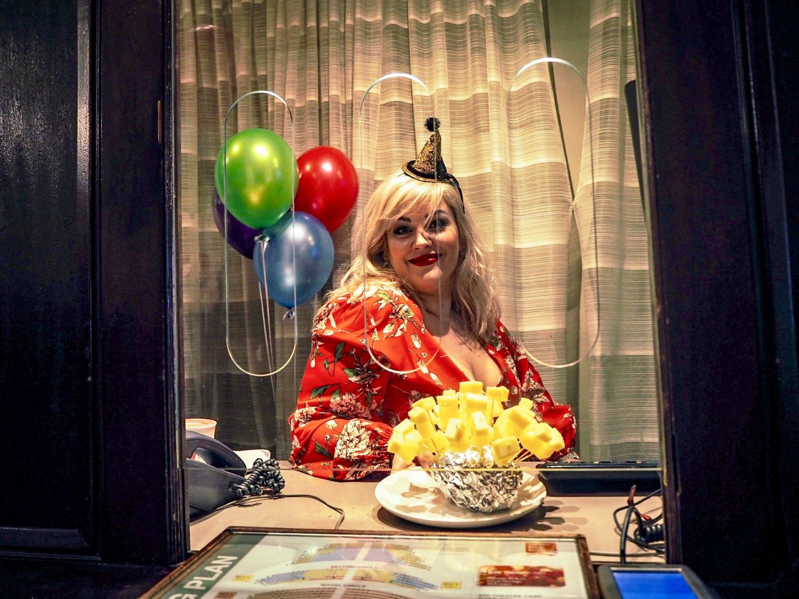 press image of jodie prenger sat at table in party hat accompanied by balloons and cheese on sticks