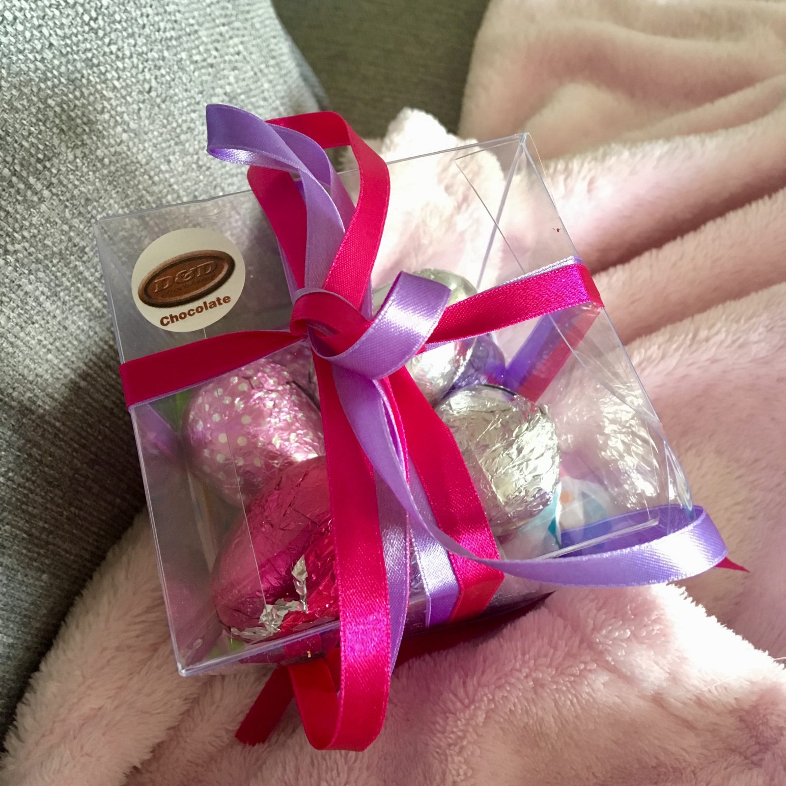 plastic box of pink and purple eggs, tied up with pink and purple ribbon