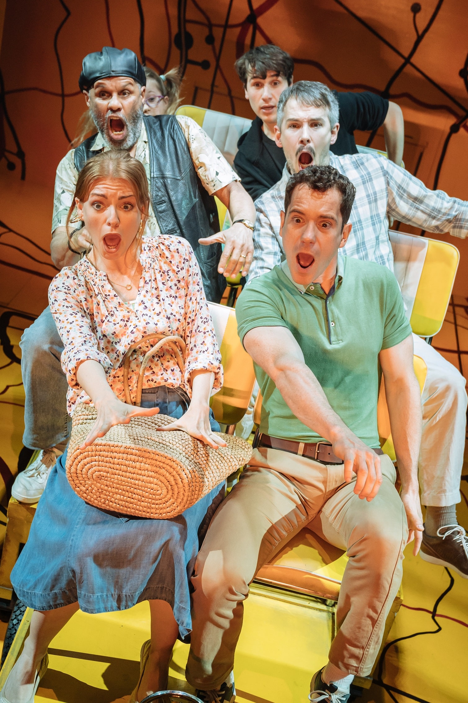 L-R from front Laura Pitt-Pulford, Gabriel Vick, Gary Wilmot, Paul Keating, Lily Mae Denman and Sev Keoshgerian onstage pulling shocked faces from seats representing the yellow campervan