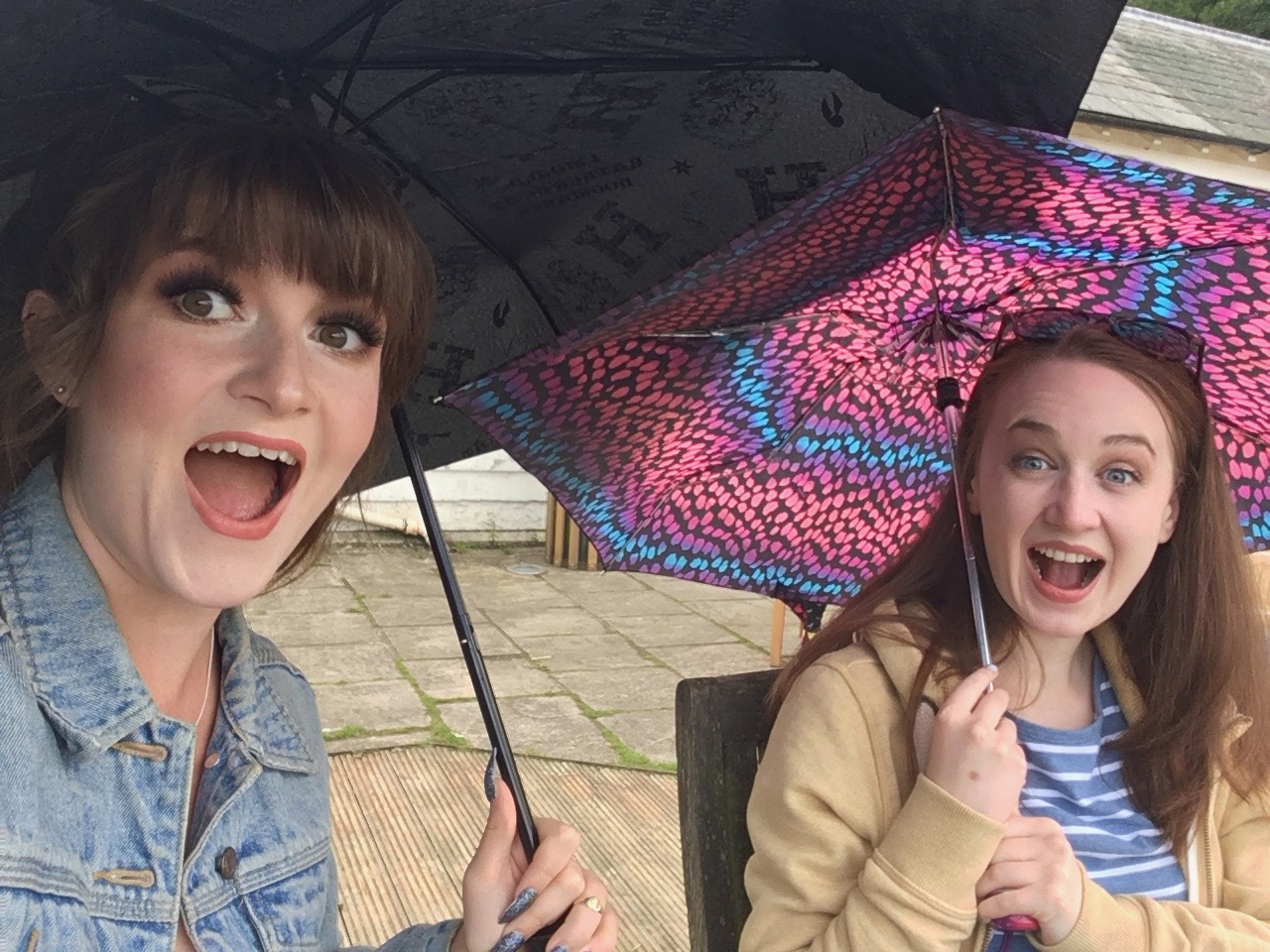 selfie of pippa and izzy both holding colourful umbrellas and pulling faces