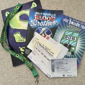 theatre programmes and tickets laid on floor, with green sunflower lanyard draped over the top