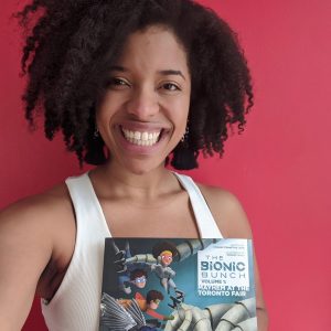 headshot selfie of kyanne stennett holding up 'the bionic bunch' children's book and smiling, against a red background