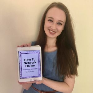 smiling headshot of pippa wearing blue short sleeved dress and brown hair down, holding up ipad displaying 'how to network online' ebook on screen