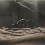 black wireless headphones laid on top of bed