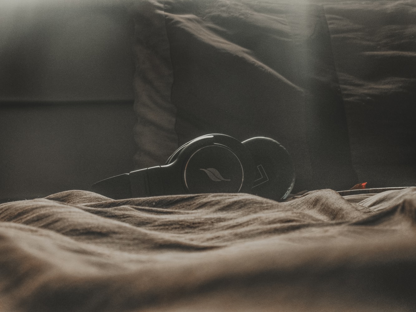 black wireless headphones laid on top of bed