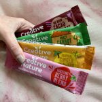 pippa's hand holding four dairy and nut free creative nature oaty bars in colourful packaging