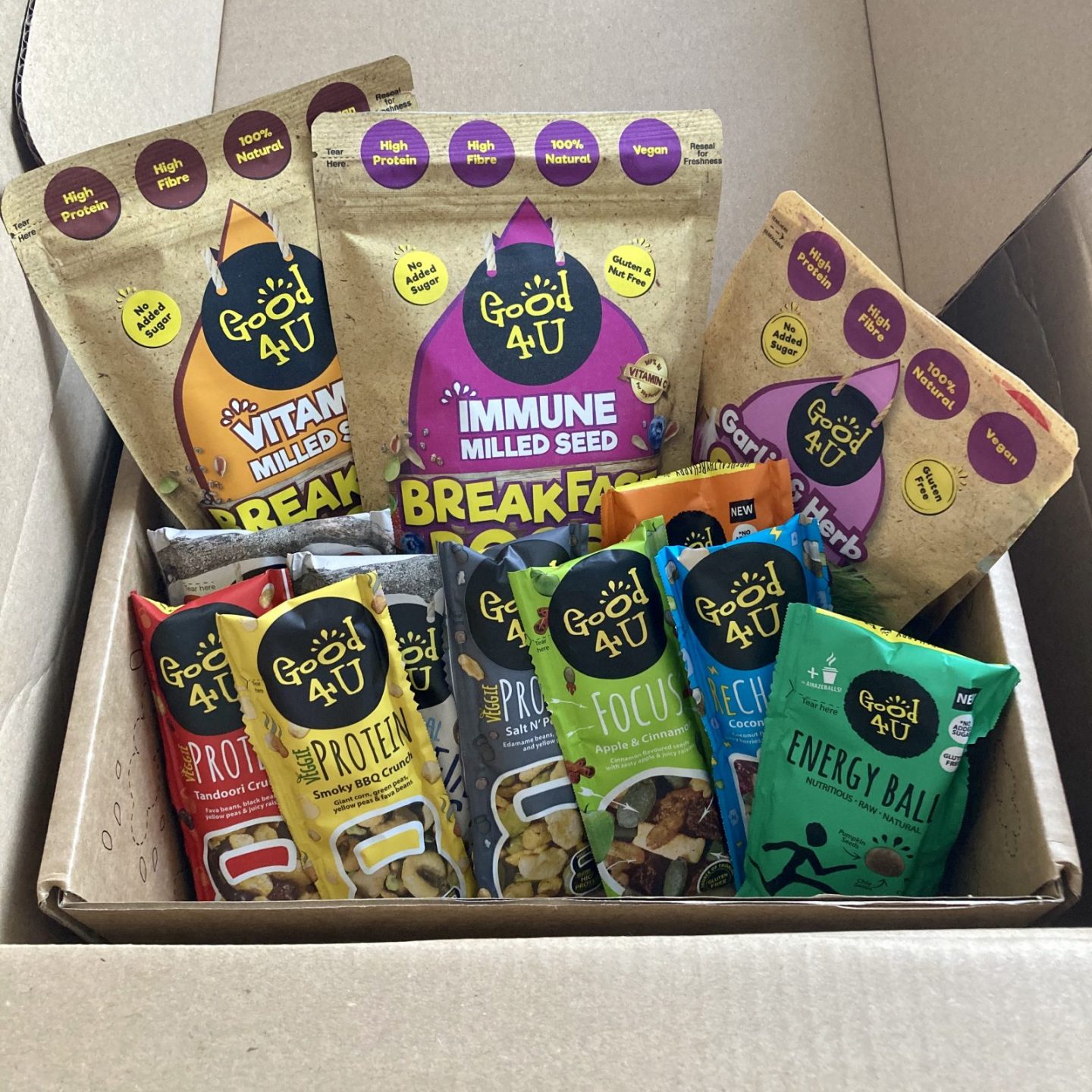 box of colourful sachets of food and snacks from good4u, including salad toppers and protein balls