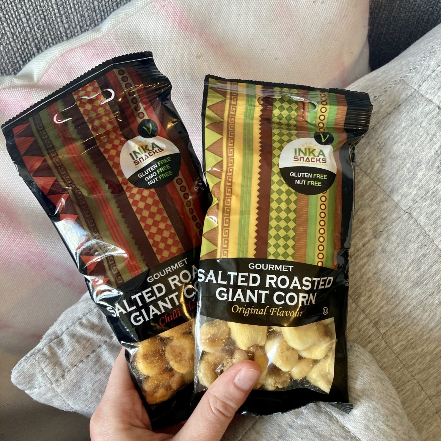 pippa's hand holding two black packets of inca snacks salted giant corn, with corn pieces visible through clear windows on packaging