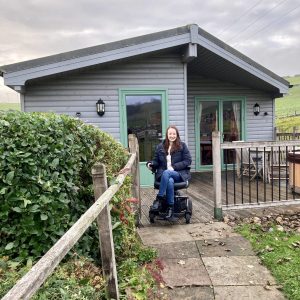 pippa in her wheelchair posing on the path leading up to daisybank cabin at hoe grange holidays