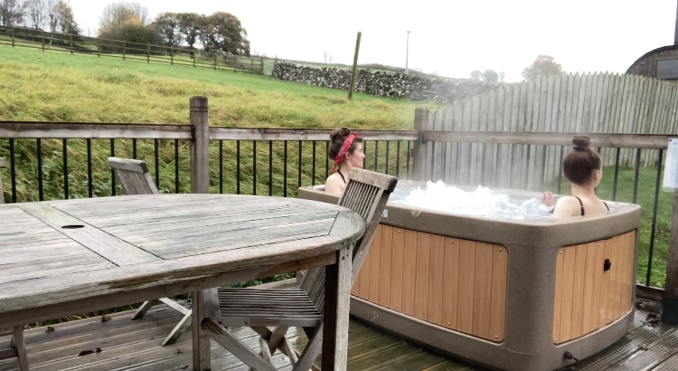izzy and pippa outdoors in hot tub, looking off to the distance at the rolling green hills all around them