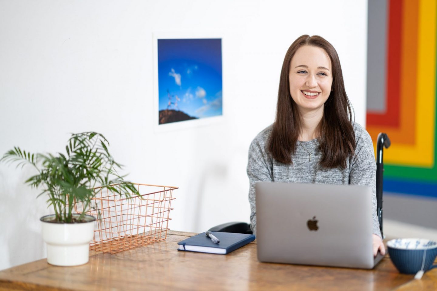 professional image of pippa sat at a desk with laptop open in front of her, looking off to the side and smiling
