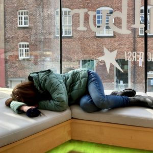 Pippa laid out on soft seating in a cafe window, legs elevated and her head resting on her hands.