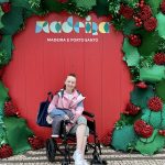pippa in her trabsit wheelchair on land in madeira in front of a festive photo board, symbolising cruising with a chronic illness
