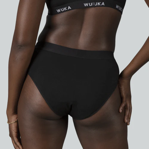 A slim black woman modelling WUKA bikini period pants and bralette in black.