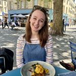 Pippa sat at an outdoor table at Boston Tea Party in Bath, with a vegan hash brown meal in front of her.