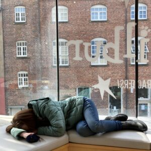 pippa flopped down on soft seating in public with her head in her hands, to represent energy limiting conditions