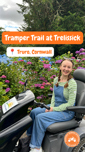 Pippa on a hired Tramper at National Trust Trelissick, with colourful borders of flowers behind her.