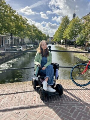 Pippa in her wheelchair on a bridge over a canal in The Netherlands, during her Amsterdam trip.